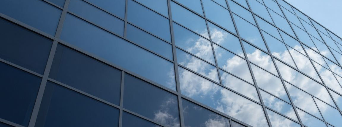 Dark glass curtain wall facade reflecting blue sky